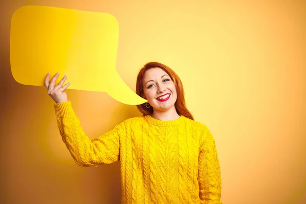 年轻美丽的红发女人拿着演讲泡泡在黄色的孤立背景与幸福的脸站立和微笑与自信的微笑显示牙齿 — 图库照片