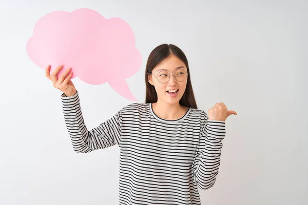 年轻的中国妇女拿着云语音泡沫在孤立的白色背景指向和显示大拇指到一边与幸福的脸微笑 — 图库照片