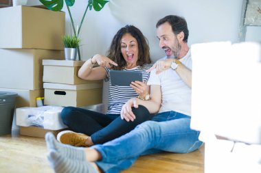 Orta yaş yaşlı çift el ve parmak ile işaret tablet kullanarak yeni bir eve hareket