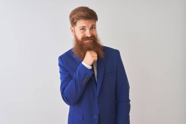 Genç kızıl saçlı İrlandalı işadamı izole beyaz arka plan üzerinde duran takım elbise giyen kamera güvenerek çapraz kollar ve el çene üzerinde kaldırdı gülümseyerek bakıyor. Olumlu düşünme.