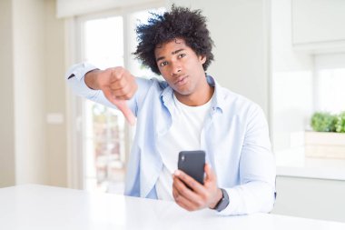 Akıllı telefon kullanan kızgın yüzü, eksi işareti aşağı antipati başparmak ile gösterilen, ret kavramı ile Afrika kökenli Amerikalı adam