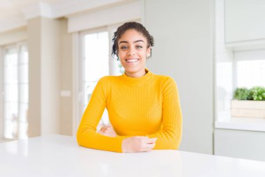 Afro saçlı güzel afro-amerikan kadın yüzünde mutlu ve serin bir gülümseme ile rahat bir sarı kazak giyiyor. Şanslı kişi.