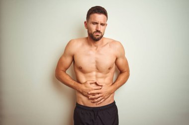 Genç yakışıklı gömleksiz adam mide üzerinde el ile izole arka plan üzerinde çünkü mide bulantısı, ağrılı hastalık kötü hissediyorum. Ağrı kavramı.