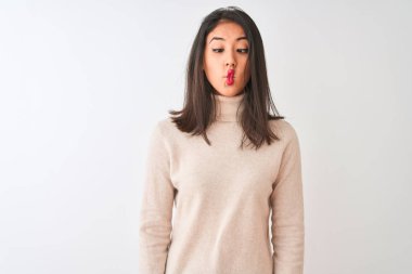 Güzel Çinli kadın dudakları, deli ve komik jest ile balık yüz yapma izole beyaz arka plan üzerinde duran boğazlı kazak giyiyor. Komik ifade.