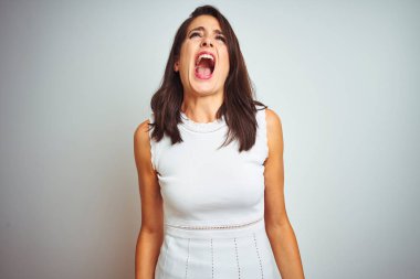 Genç güzel kadın beyaz izole arka plan üzerinde duran elbise giyen kızgın ve deli çığlık sinirli ve öfkeli, öfke ile bağırarak. Öfke ve agresif kavram.