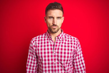 Kırmızı izole arka plan şüpheci ve sinir üzerinde Genç yakışıklı adam, sorun nedeniyle üzgün kaşlarını çatma. Negatif kişi.