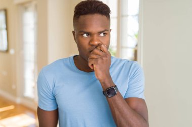 Yakışıklı afro-amerikan adam rahat t-shirt görünümlü stresli ve sinirli elleri ağız tırnakısırma ile. Anksiyete sorunu.