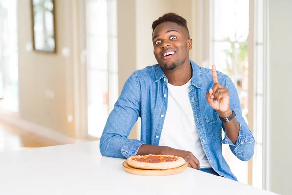 Afro Americano Comendo Pizza Pepperoni Casa Surpreso Com Uma Ideia — Fotografia de Stock