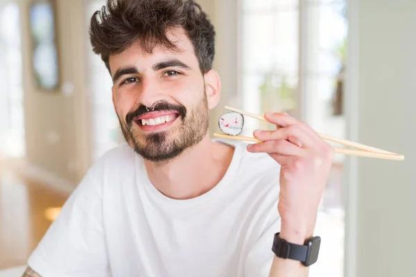Νέος Άνθρωπος Τρώει Ασιατικό Σούσι Χρησιμοποιώντας Ξυλάκια Ένα Χαρούμενο Πρόσωπο — Φωτογραφία Αρχείου