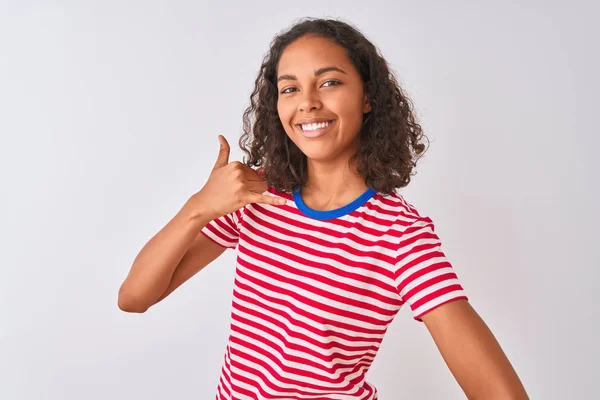 赤い縞模様のTシャツを着た若いブラジル人女性は 孤立した白い背景の上に立ち 電話で話すような手と指で電話ジェスチャーをして微笑んでいる 概念の伝達 — ストック写真