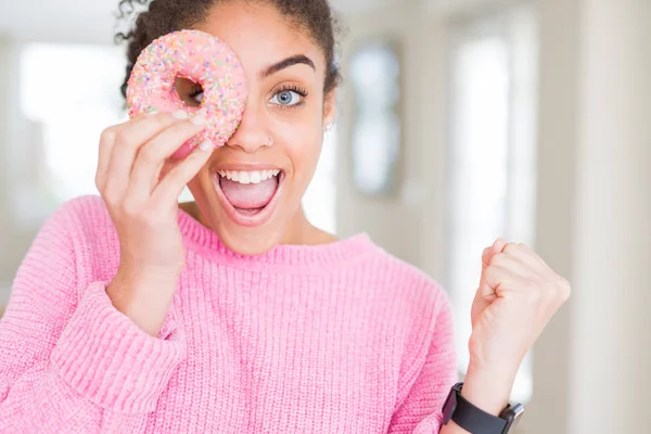 甘いピンクのドーナツを食べる若いアフリカ系アメリカ人の女の子は誇らしげに叫び 勝利と成功を祝う非常に興奮し 感情を応援 — ストック写真