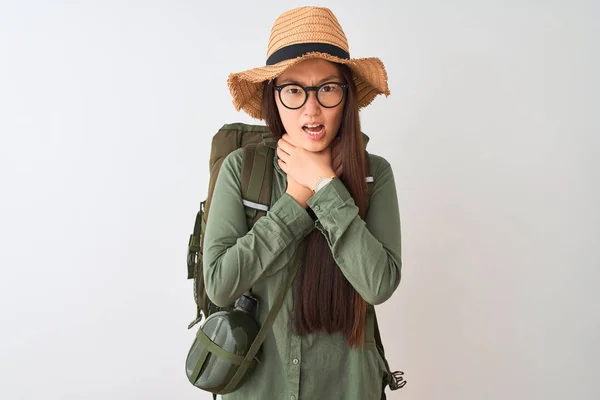 Chinese hiker woman wearing canteen hat glasses backpack over isolated white background shouting and suffocate because painful strangle. Health problem. Asphyxiate and suicide concept.