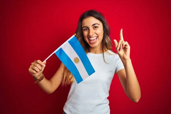Νέα Όμορφη Γυναίκα Κρατώντας Σημαία Αργεντινής Πάνω Από Κόκκινο Απομονωμένο — Φωτογραφία Αρχείου