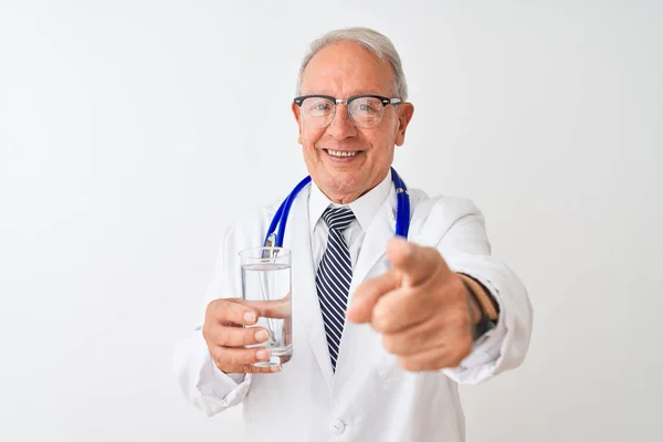 Starszy Siwy Lekarz Człowiek Picie Szklanki Wody Białym Tle Wskazując — Zdjęcie stockowe