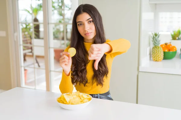 怒った顔でファーストフードポテトチップスを食べる若い女性 親指を下にして嫌いを示す否定的なサイン 拒絶概念 — ストック写真