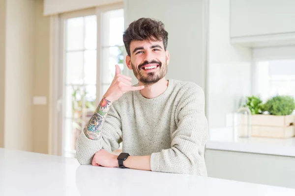 Junger Mann Lässigem Pullover Sitzt Auf Weißem Tisch Und Lächelt — Stockfoto