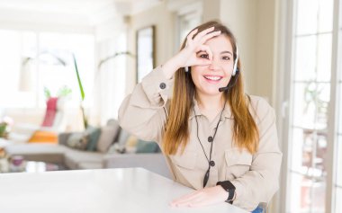 Ofiste kulaklık takan güzel genç operatör kadın el gülümseyerek ok jest yapıyor, mutlu yüz ile parmaklardan bakan göz.