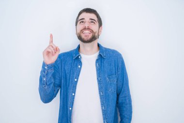 Genç yakışıklı İspanyol adam başarılı bir fikir ile parmak işaret beyaz izole arka plan üzerinde kot ceket giyiyor. Çıktı ve mutlu. Bir numara.