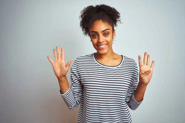 African american woman wearing navy striped t-shirt standing over isolated white background showing and pointing up with fingers number nine while smiling confident and happy.