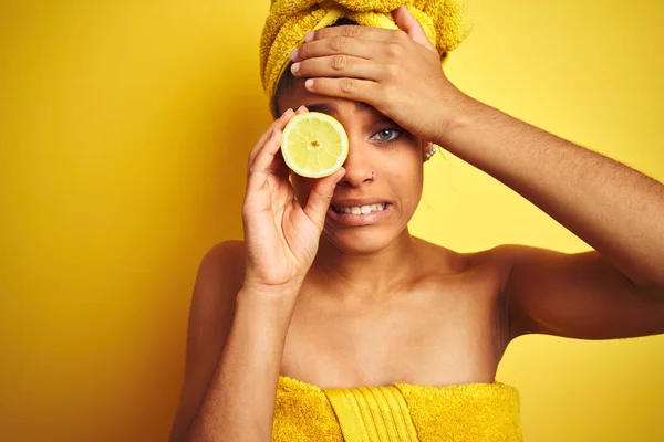 孤立した黄色の背景の上にスライスレモンを保持した後にタオルを着用したアフロ女性は 頭の上に手で強調し 恥と驚きの顔でショックを受け 怒りとイライラ 間違いに対する恐怖と動揺 — ストック写真