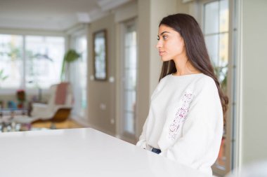 Genç güzel kadın evde tarafına bakarak beyaz masaya dinlenmek doğal yüz emin gülümseme ile pozuyla profili.