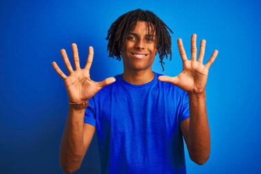 Afro amerikan adam dreadlocks giyen t-shirt izole mavi arka plan üzerinde duran gösteren ve parmakları ile işaret on numara ile gülümseyerek emin ve mutlu.