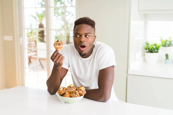 Afričan Americký Muž Pojídáním Čokoládových Čipů Muffin Vystrašený Šoku Překvapením — Stock fotografie