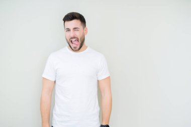 Genç yakışıklı adam giyiyor rahat beyaz t-shirt dilini izole arka plan üzerinde out komik ifade ile mutlu. Duygu kavramı.