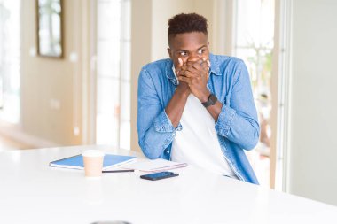 Dizüstü bilgisayar kullanan ve kulaklık takan Afro-Amerikalı öğrenci hata için ağzı yla kaplayarak şok elendi. Gizli kavram.