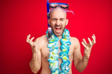 Dalgıç şnorkel gözlükleri ve hawaii li çiçeklerini izole kırmızı arka plan üzerinde giyen genç adam, kollarını kaldırıp kapalı gözleri ile başarı için deli ve deliliği kutluyor ve heyecan çığlıklar atıyor. Kazanan kavramı