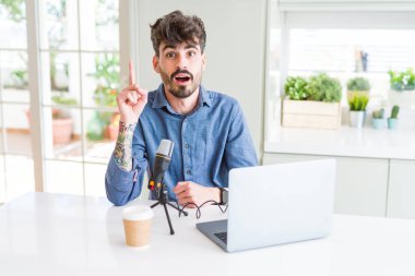 Genç adam başarılı bir fikir ile mikrofon ve dizüstü işaret parmak kullanarak podcast kayıt. Çıktı ve mutlu. Bir numara.