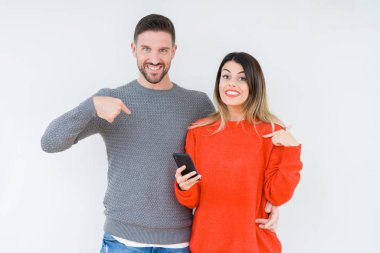 Kendine işaret sürpriz yüz ile izole arka plan üzerinde akıllı telefon kullanan genç çift