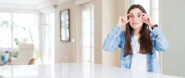 Evde beyaz masada oturan güzel genç kadının geniş açılı resmi sabah yorgunluğu için uykulu ve yorgun parmaklarıyla gözleri açmaya çalışıyor