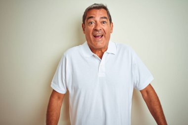 Izole beyaz arka plan üzerinde duran polo giyen yakışıklı orta yaş adam korkmuş ve sürpriz ifade ile şok, korku ve heyecanlı yüz.