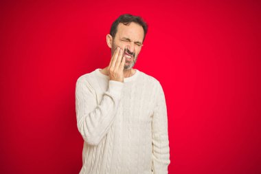 Izole kırmızı arka plan üzerinde gri saçlı yakışıklı orta yaş yaşlı adam diş ağrısı veya diş üzerinde diş hastalığı nedeniyle ağrılı ifade ile el ile ağız dokunmadan. Diş hekimi konsepti.