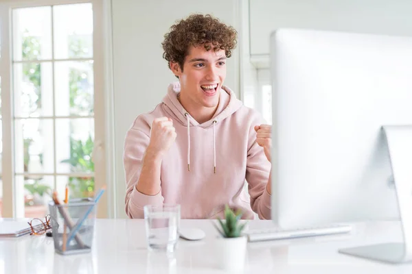 Young student man using computer screaming proud and celebrating victory and success very excited, cheering emotion