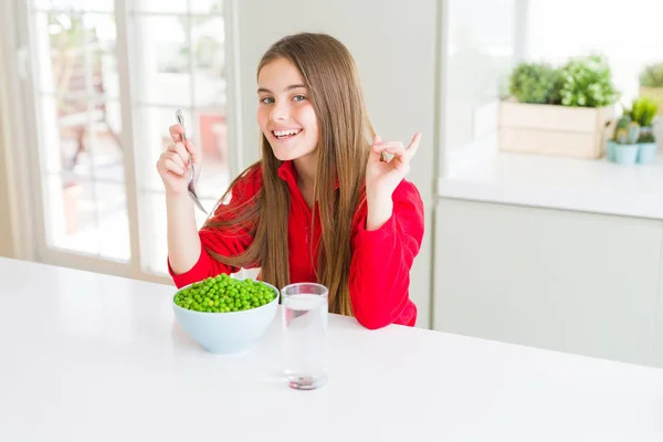 健康的な緑のエンドウ豆を食べる美しい若い女の子は 側に手と指で指を指して非常に幸せ — ストック写真