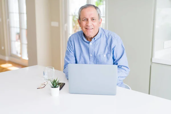 Красивый пожилой человек с ноутбуком и улыбкой — стоковое фото