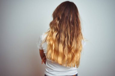 Izole arka plan üzerinde rahat beyaz t-shirt giyen genç güzel kadın çapraz kolları ile geriye bakarak geriye doğru duran