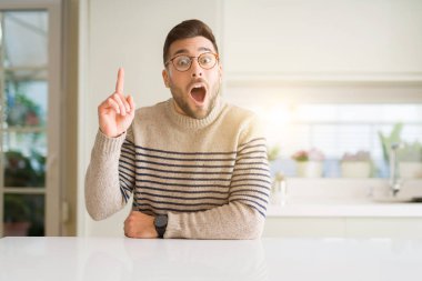 Evde gözlük takan genç yakışıklı adam başarılı bir fikirle parmağını yukarı yasladı. Çıktı ve mutlu. Bir numara.