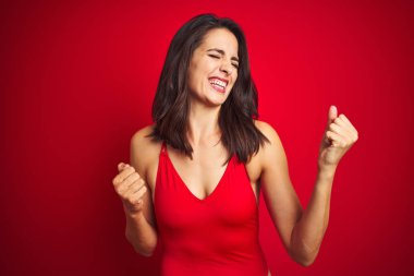 Kırmızı izole arka plan üzerinde bikini mayo giyen güzel kadın çok mutlu ve heyecanlı kolları kaldırdı ile kazanan jest yapıyor, gülümseyerek ve başarı için çığlık. Kutlama konsepti.