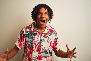 Tatilde dreadlocks ile Afro adam izole beyaz arka plan üzerinde yazlık gömlek giyen deli kutluyor ve silah kaldırdı ve açık gözleri ile başarı için hayran heyecanlı çığlık. Kazanan kavramı