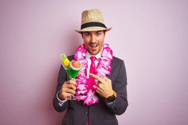 Takım elbise şapka hawaiian lei içme kokteyli giyen işadamı izole pembe arka plan üzerinde çok mutlu el ve parmak ile işaret