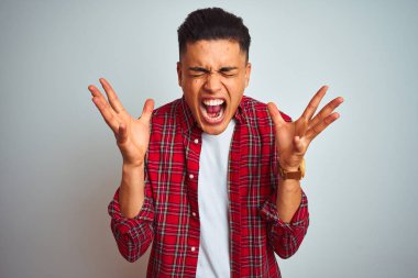 Kırmızı gömlek giyen genç brezilyalı adam izole beyaz arka plan üzerinde ayakta silah kaldırdı ve kapalı gözleri heyecan çığlık ile başarı için deli ve deli kutluyor. Kazanan kavramı