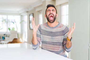 Yakışıklı İspanyol adam evde rahat kazak giyen silah kaldırdı ve kapalı gözleri heyecan çığlık ile başarı için deli ve deli kutluyor. Kazanan kavramı