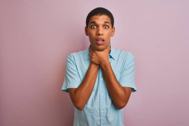 Genç yakışıklı Arap adam izole pembe arka plan üzerinde duran mavi gömlek giyen bağırarak ve boğulma kısık çünkü acı boğmak. Sağlık sorunu. Boğulma ve intihar kavramı.