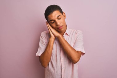 Genç yakışıklı arap adam izole pembe arka plan üzerinde duran rahat gömlek giyen yorgun rüya ve kapalı gözlerle gülümseyerek birlikte elleri ile poz.