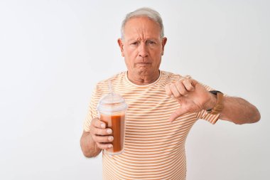 Kızgın yüz ile izole beyaz arka plan üzerinde çizgili t-shirt içme domates smoothie giyen Kıdemli adam, başparmak aşağı, ret kavramı ile sevmediğimi gösteren negatif işareti