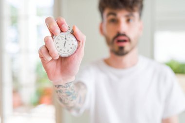 Stopwatch tutan kullanan genç adam sürpriz bir yüz ile şok korkmuş, korku ifade ile korkmuş ve heyecanlı