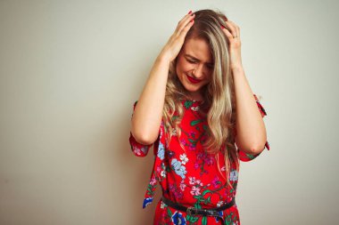 Genç güzel kadın beyaz izole arka plan üzerinde çiçek t-shirt giyen baş ağrısı umutsuz muzdarip ve stresli çünkü ağrı ve migren. Eller baş üstünde.